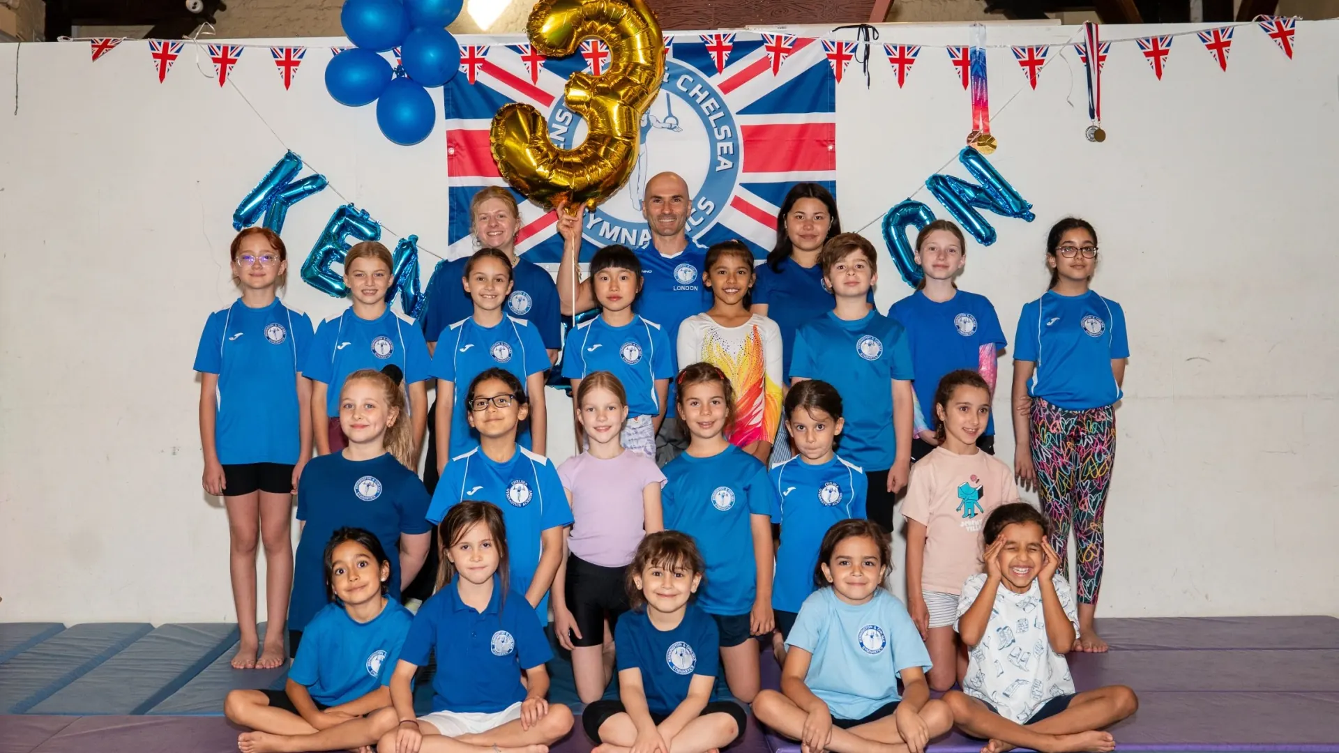 Kensington & Chelsea Gymnastics Academy coaches and children posing together at St Philip’s Church in Kensington, London.