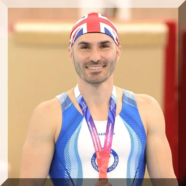 Head Coach Stefan from Kensington & Chelsea Gymnastics smiling with medals in London.