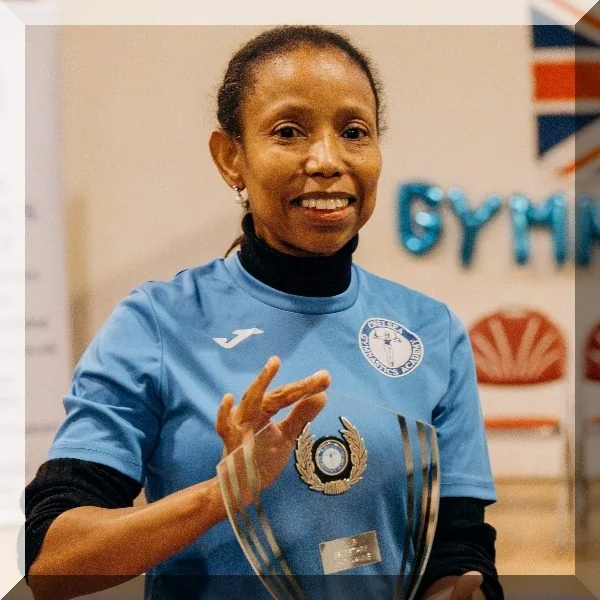 Mary-Anne, Welfare Officer at Kensington & Chelsea Gymnastics, smiling in blue club shirt.