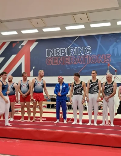 Coach Stefan Kolimechkov standing among fellow masters gymnasts at the 2023 British Gymnastics Adult Championships.