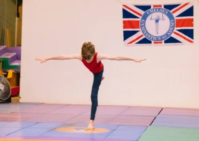 Primary school boy gymnast performing an arabesque pose during the Annual Performance 2023 in Kensington, London.