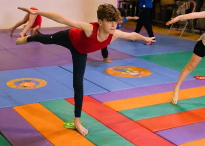 Young male gymnast performing a balance pose (arabesque) during the Annual Performance 2023 in Kensington.