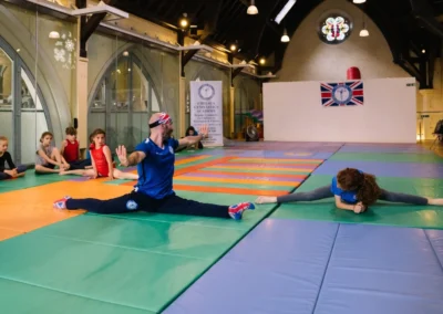 Coach Stefan and gymnast showing flexibility with full splits during the Annual Performance 2023 at KCGA in Kensington.