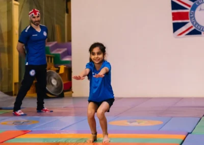 Young gymnast holding a landing position at the end of her routine during the Annual Performance 2023 in Kensington, London.