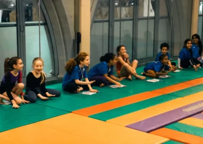Young gymnasts laughing and watching at KCGA Easter gymnastics classes in Kensington London W8.