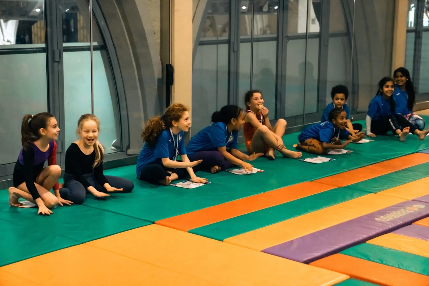 Young gymnasts laughing and watching at KCGA Easter gymnastics classes in Kensington London W8.