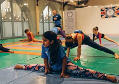 Young gymnast stretching in splits during KCGA Easter gymnastics warm-up in Kensington London W8.