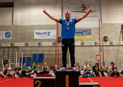 Rings champion on first place podium at Milton Keynes Gymnastics masters competition in England.