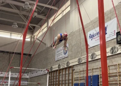 Artistic gymnast holding a planche on still rings at Milton Keynes competition in England.