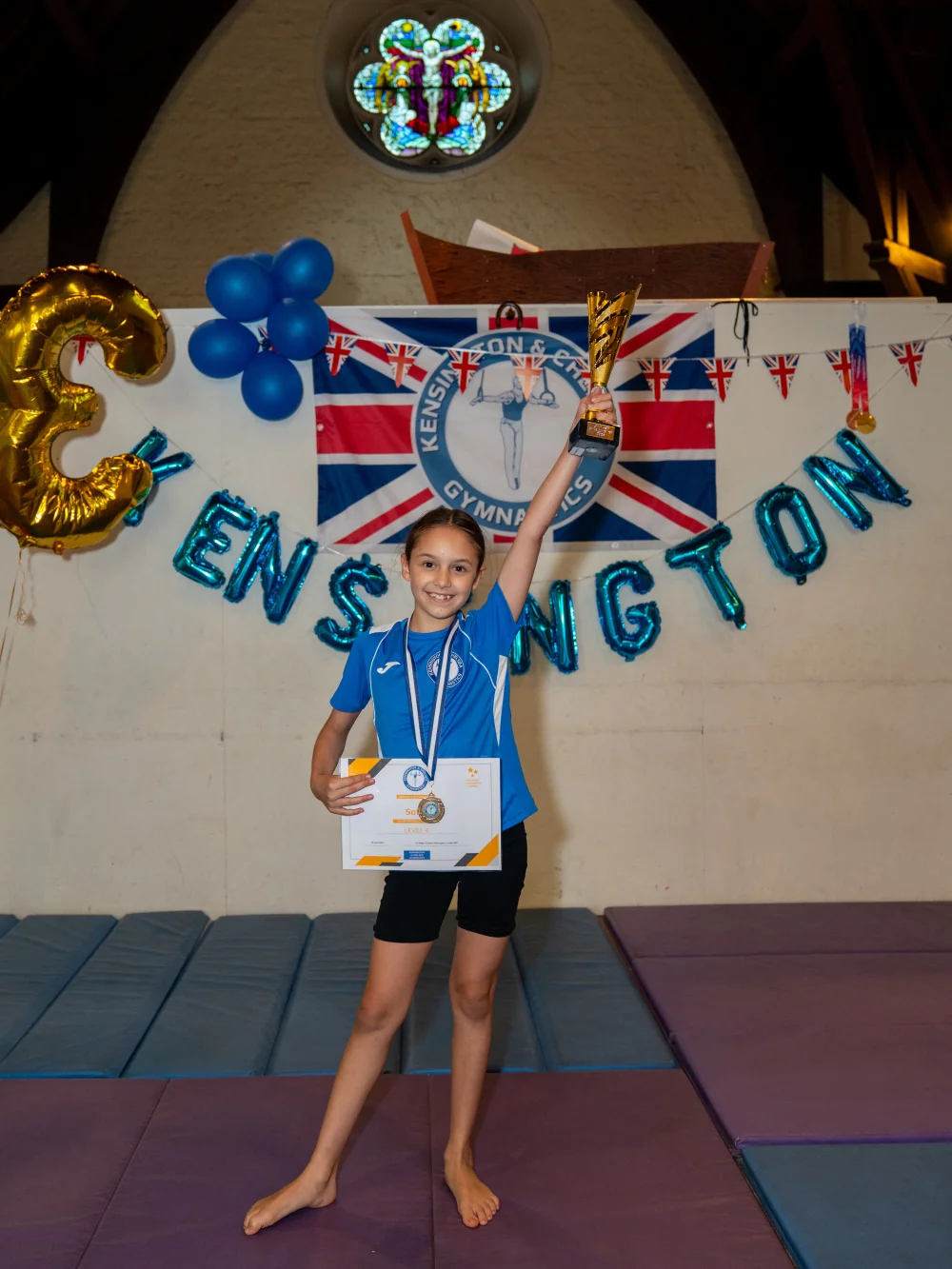 Sofia proudly holding her trophy and gold medal at KCGA’s Annual Performance in Kensington