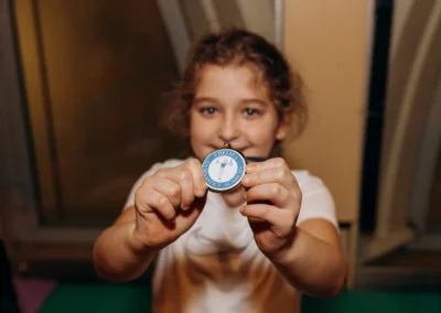 Child holding up a Chelsea Gymnastics Academy medal at the 2023 Christmas showcase.
