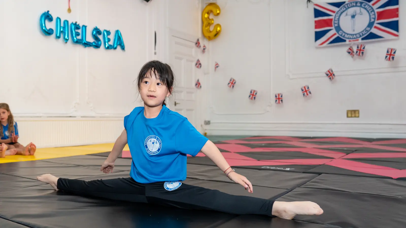 Young gymnast performing a split during a children’s gymnastics class at Chelsea Gymnastics, showcasing confidence, flexibility, and strong technique.