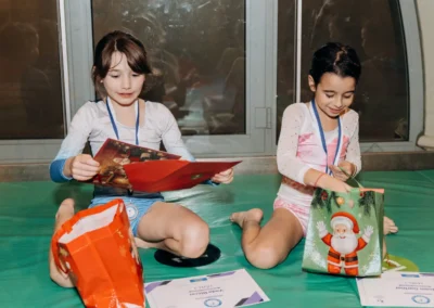 Two young gymnasts opening their Christmas cards and presents at the KCGA showcase.