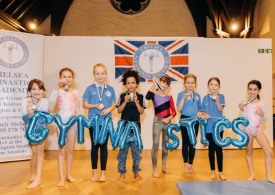 Group of young gymnasts proudly holding their medals at the Christmas 2023 Chelsea Gymnastics Academy event.
