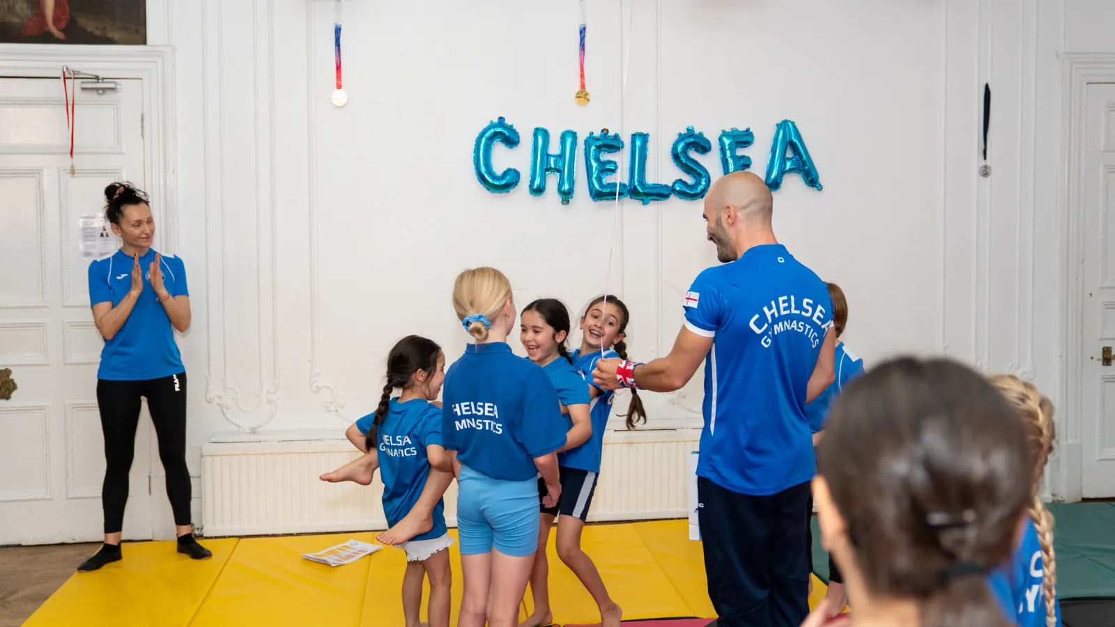 Smiling children practising gymnastics with their coaches at Chelsea Gymnastics during a fun and supportive session in Chelsea SW3.