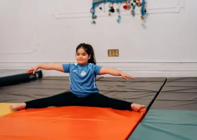 Child performing a straddle sit during a gymnastics class for children in Knightsbridge SW1X