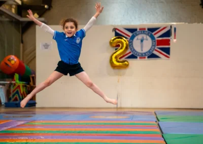 Child gymnast performing a star jump during the KCGA Annual Performance in Kensington