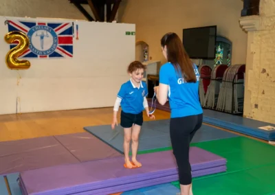 Coach awarding medal to young child at gymnastics performance in Kensington London