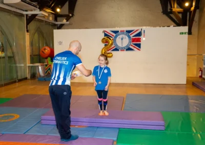 Coach presenting certificate to child at gymnastics performance in Kensington London
