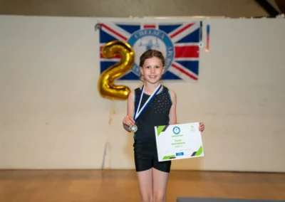 Child holding gymnastics certificate and medal at Annual Performance in Kensington London