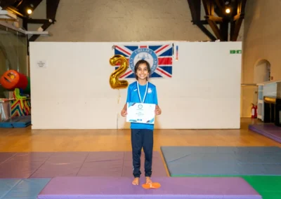 Child standing with gymnastics certificate at Annual Performance in Kensington London