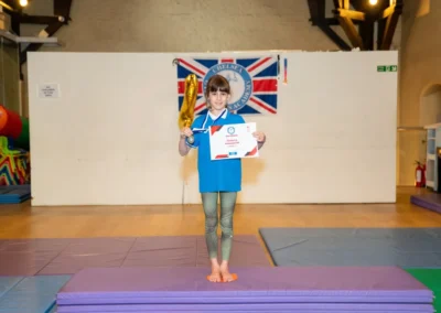 Child holding gymnastics certificate and trophy at Annual Performance in Kensington London