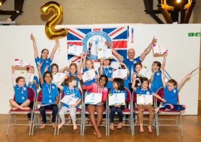 Children celebrating with certificates at gymnastics performance in Kensington London