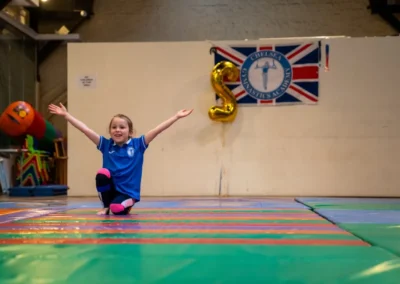 Child presenting kneeling pose during gymnastics performance in Kensington London