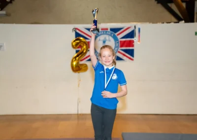 Child holding the trophy Gymnast of the Year for 2024 in celebration at gymnastics performance in Kensington London