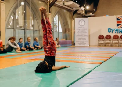 A young gymnast performing a shoulder stand at the KCGA Christmas 2023 performance in Kensington London.