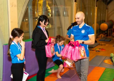 Coach presenting Easter gifts and medals to children during Easter 2025 gymnastics classes in Kensington London
