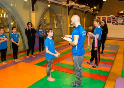 Easter 2025 children’s gymnastics class in Kensington – coach gives individual feedback while group watches at KCGA.