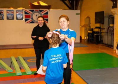 Child receiving a gymnastics medal during Easter 2025 celebration at Kensington and Chelsea Gymnastics Academy