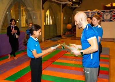 Easter 2025 gymnastics in Kensington at St Philip’s Church – coach and child review a certificate celebrating progress at KCGA.