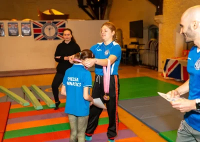 Easter 2025 gymnastics in Kensington – coach awards a medal to a child gymnast at KCGA’s celebration session.