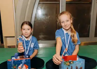 Two gymnasts smiling and showing candy canes at KCGA’s Christmas gymnastics celebration.