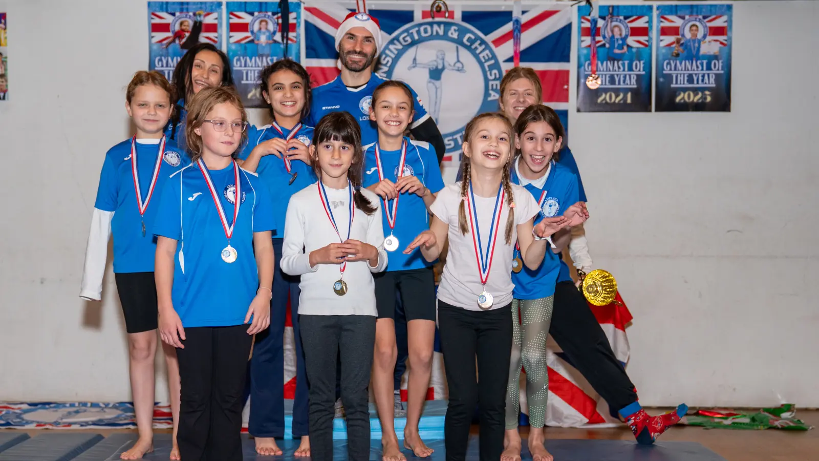 Group of children at Kensington & Chelsea Gymnastics smiling with medals after class, representing healthy development, confidence, and community.