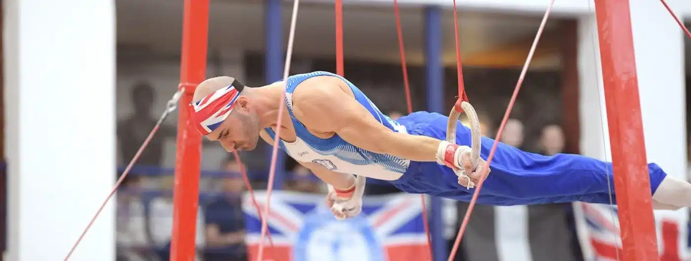 Dr Stefan Kolimechkov performing a strength hold on rings during a Masters gymnastics competition in the UK