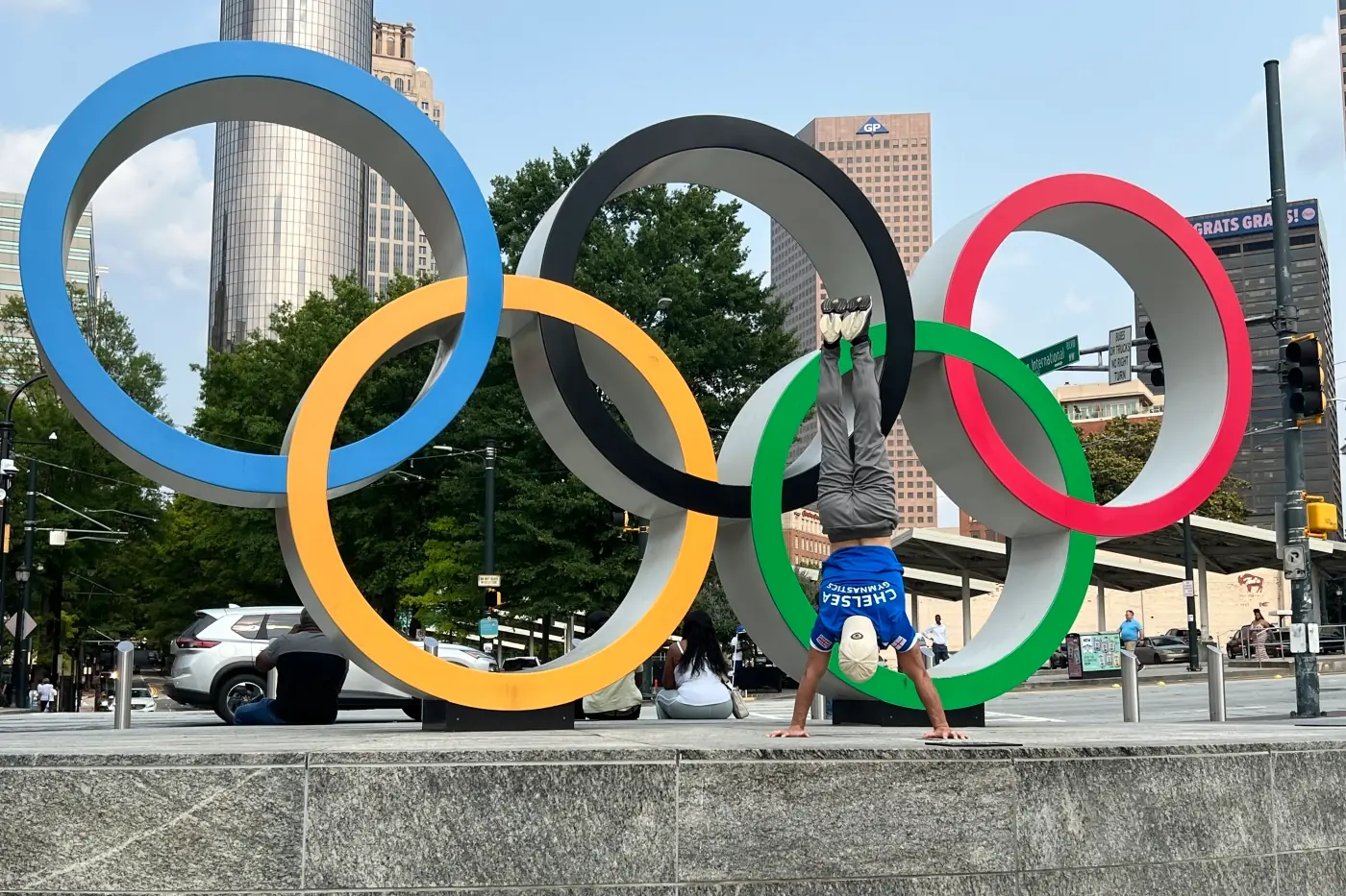 Dr Stefan Kolimechkov performing a handstand in front of the Olympic Rings at Centennial Olympic Park during the ACSM 2025 Meeting in Atlanta