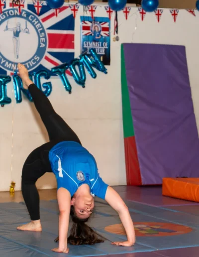 Adult female gymnast performing a bridge kickover on mats at KCGA Annual Performance in Kensington