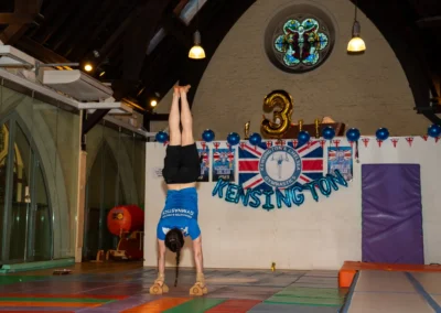 Adult gymnast performing controlled handstand on wooden bars at KCGA Annual Performance 2025 in Kensington London