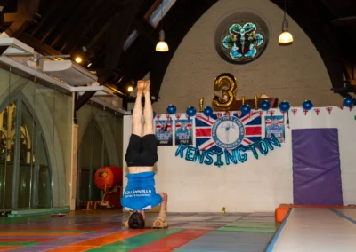 Adult gymnast balancing in headstand on bars at KCGA Annual Performance in Kensington London