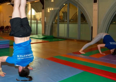 Adult gymnast performing headstand on gymnastics mat at KCGA Annual Performance Kensington
