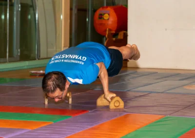 Adult male gymnast performing advanced planche variation on parallettes at KCGA 2025 Annual Performance Kensington London