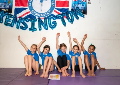 Young gymnasts celebrating under Kensington Gymnastics banner at Annual Performance