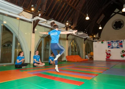 Adult gymnast performing a controlled jump and balance exercise during an adult gymnastics class in Kensington, London.