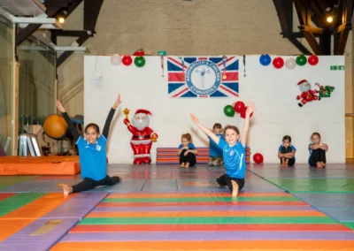 Children demonstrating cross-split flexibility during the KCGA Christmas 2024 event at Kensington Gymnastics Club