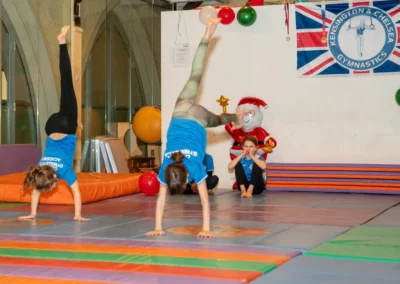 Children practising kick-to-handstand exercises during the KCGA Christmas 2024 event at Kensington Gymnastics Club
