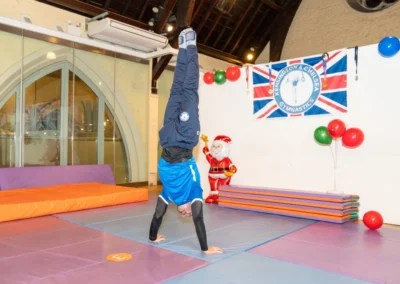 KCGA coach demonstrating a handstand during the Christmas 2024 event at Kensington Gymnastics Club