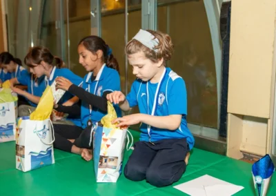 Children opening Christmas gifts during gymnastics celebration at Kensington Gymnastics Club